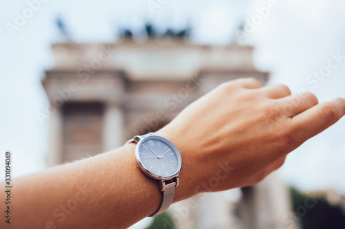 Valokuvatapetti Cropped image of female's hand with modern elegant metallic timepiece on blurred