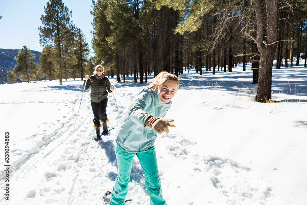 Thirteen year old girl and her mother on snow shoes on a trail in snow. ,Valle Caldrea Thirteen year old girl and her mother on snow shoes on a trail in snow. ,Valle Caldrea