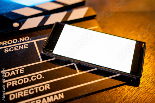 Fényképezés mobile phone with empty white bright screen movie clapper board