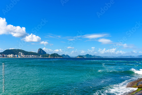 Sunny day at Copacabana beach with the hills of Rio de Janeiro in the background
