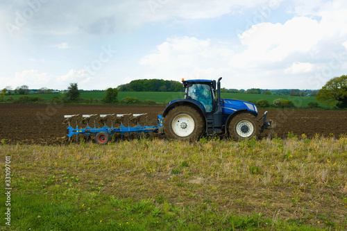 A tractor harrowing, ploughing in the stubble in a field. ,Farming photo