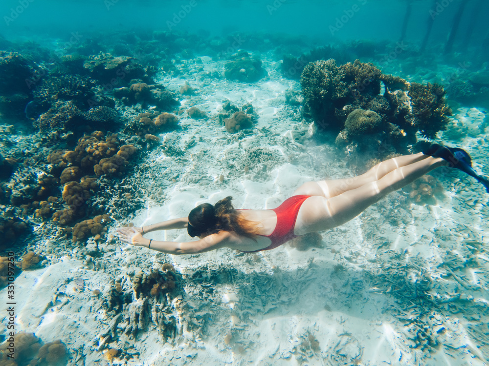 Young woman snorkeling in sea near coral reef