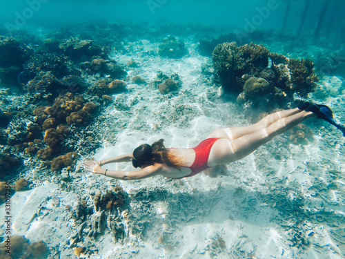 Young woman snorkeling in sea near coral reef