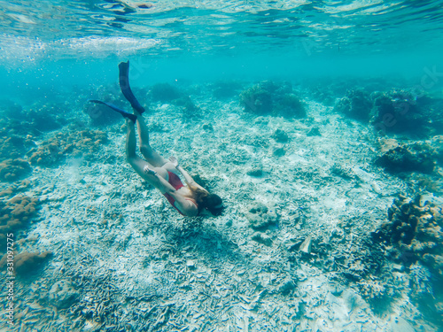 Travel woman diving into crystal blue ocean with beautiful coral reef for exploring tropical underwater, girl in red bikini enjoying snorkeling getaway for discovering ocean in swim fins