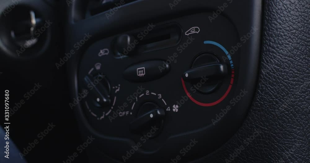 Driver adjusting the interior temperature of a car while driving to blowing hot air with maximum power.
