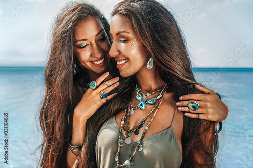 close up of two cheerful young women sisters twins on the beach