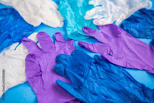 Pile of multicolored multiple medical latex gloves top view on a blue background. Coronavirus protection.