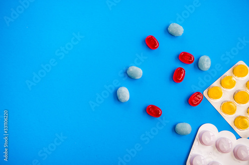 Flat lay composition with bunch of different colorful pills and blister packs in the corner. Pile of unpacked medication on paper textured background. Close up, copy space.