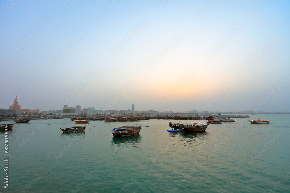 Fototapeta premium A tranquil scene of various traditional wooden ships in the shores of Doha, Qatar.