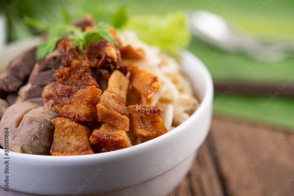 Yellow noodles in a cup with crispy pork, slices of pork, and meatballs together with Thai food-style noodles Yellow noodles in a cup with crispy pork, slices of pork, and meatballs together with Thai food-style noodles