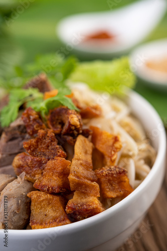 Yellow noodles in a cup with crispy pork  slices of pork  and meatballs together with Thai food-style noodles