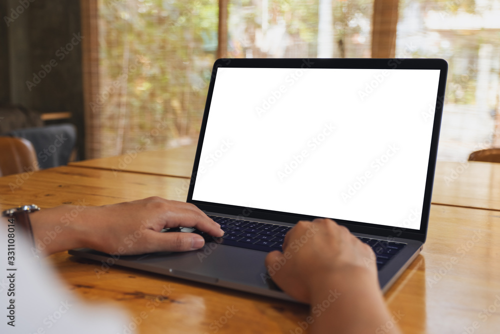 Mockup image of a woman using and typing on laptop computer with blank white desktop screen on wooden table Mockup image of a woman using and typing on laptop computer with blank white desktop screen on wooden table