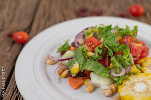 Fruit and vegetable salad on a white plate on a wooden floor