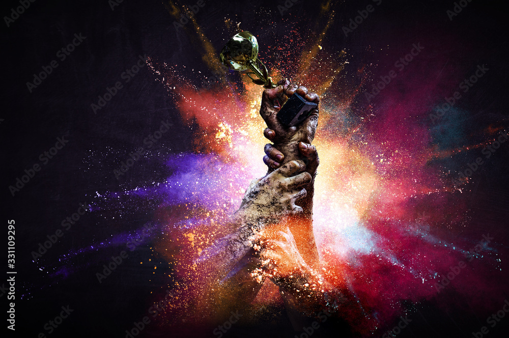 Hand holding up a gold trophy cup against dark background Hand holding up a gold trophy cup against dark background