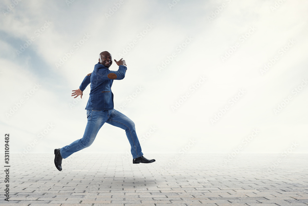 Joyful black man wearing casual clothes running around. Mixed media Joyful black man wearing casual clothes running around. Mixed media