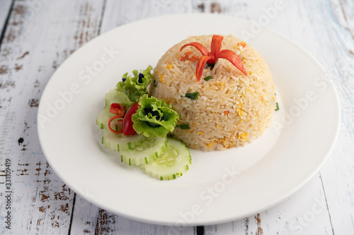 Fried rice with eggs in a white plate on wood background.