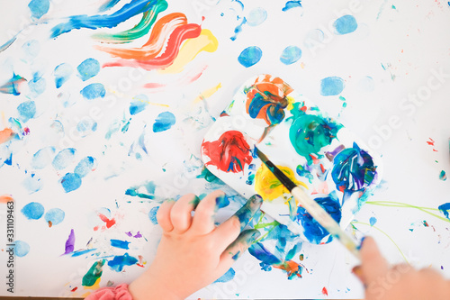 A child is painting with fingers and brush and oil paints