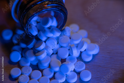 Medicine in form of pills under blue light on wooden table. Pharmaceutical tablets for health. Health care prescription