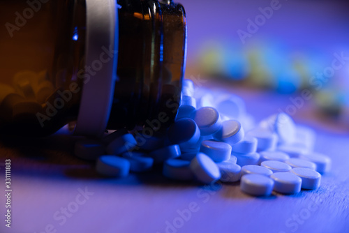 Opioids in a glass bottle. Opioid epidemic. Tablets and pills under blue light. Closeup of medicinals and pain killers.