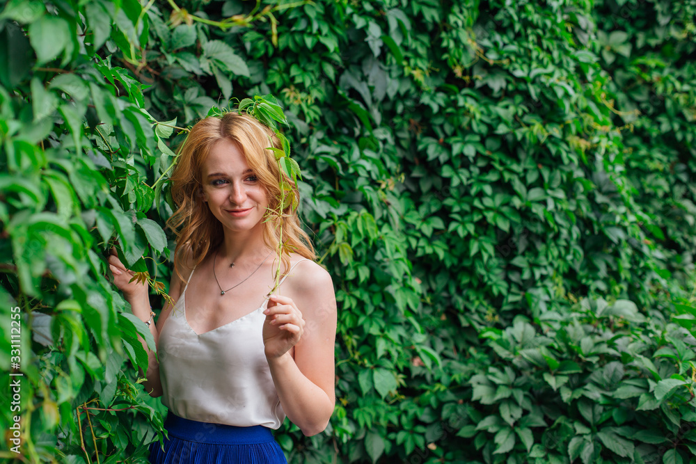 Portrait of a young beautiful woman, standing next to the wall of wild grape leaves. Portrait of a young beautiful woman, standing next to the wall of wild grape leaves.
