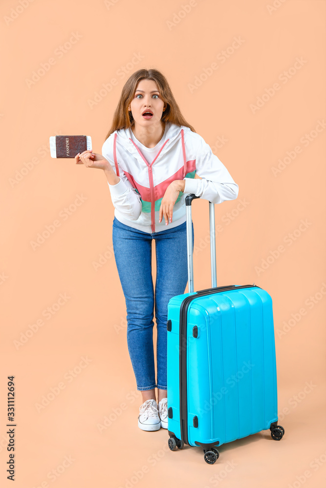 Shocked female tourist with luggage on color background Shocked female tourist with luggage on color background