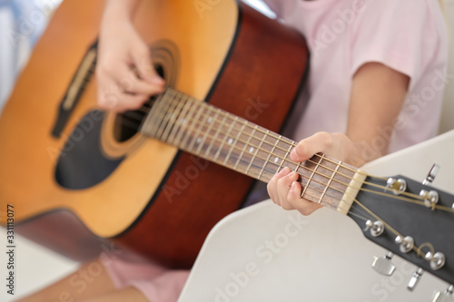 Private music teacher giving guitar lessons to little girl at home, closeup