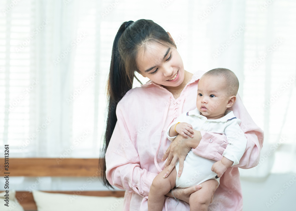 family, child and parenthood concept - happy beautiful young asian mother smiling hugging holding newborn baby in her arms at home. Banner with copy space for advertise family, child and parenthood concept - happy beautiful young asian mother smiling hugging holding newborn baby in her arms at home. Banner with copy space for advertise