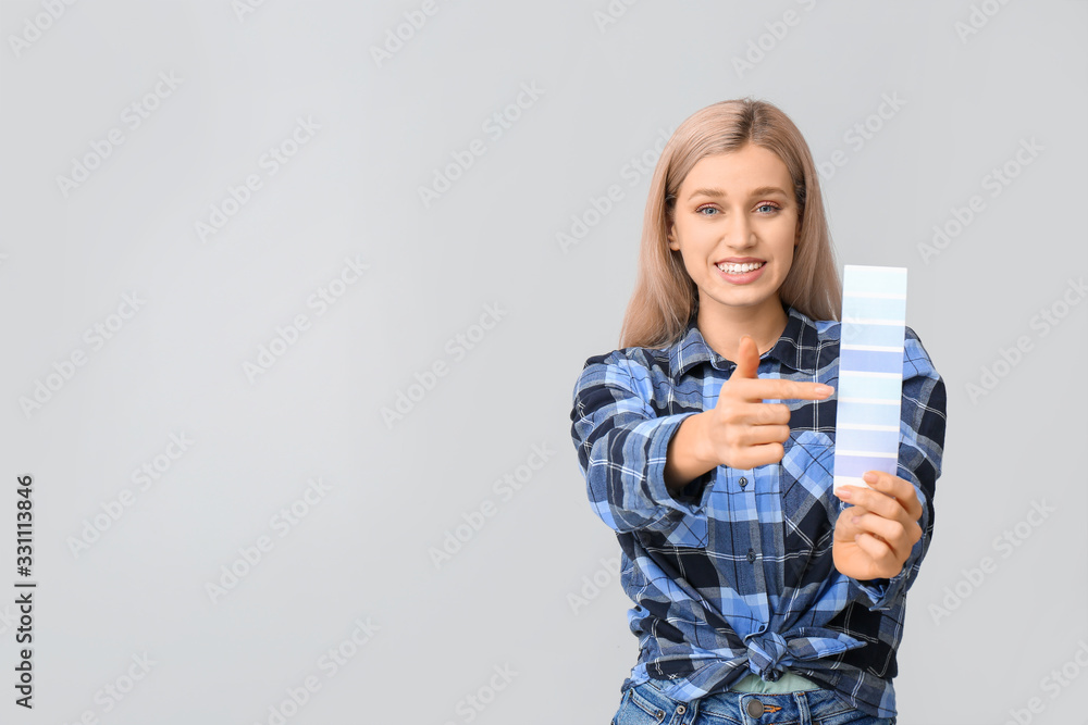Young woman with color swatches on grey background Young woman with color swatches on grey background