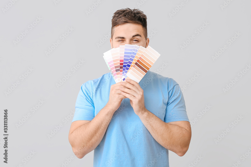 Young man with color swatches on grey background Young man with color swatches on grey background