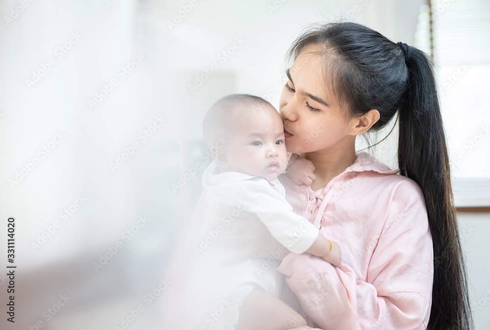 family, child and parenthood concept - happy beautiful young asian mother smiling hugging holding newborn baby in her arms at home. Mother’s day banner with copy space for advertise family, child and parenthood concept - happy beautiful young asian mother smiling hugging holding newborn baby in her arms at home. Mother’s day banner with copy space for advertise