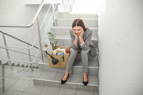 Sad fired woman sitting in the stairway