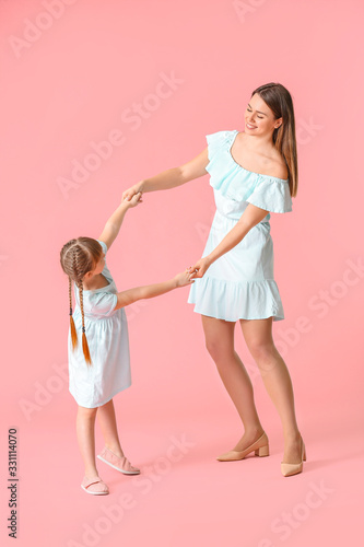 Happy mother and her little daughter dancing against color background © Pixel-Shot