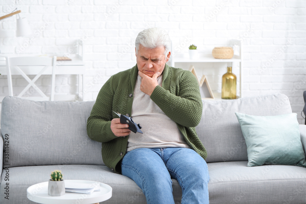 Sad senior man with purse at home Sad senior man with purse at home