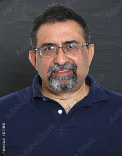 Quadro em tela An Indian man with a goatee beard wearing spectacles against a dark background