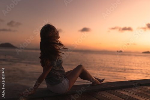 Beautiful girl at sunset on the sea in Thailand. Bright orange and yellow pink sky. Girl traveler enjoys the view. Woman in the tropics © Underwater girls
