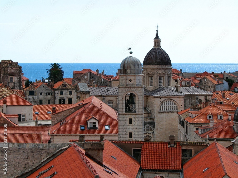 view of Dubrovnik from the fortress wall, you can see the old Cathedral, houses with red roofs and a blue strip of sea