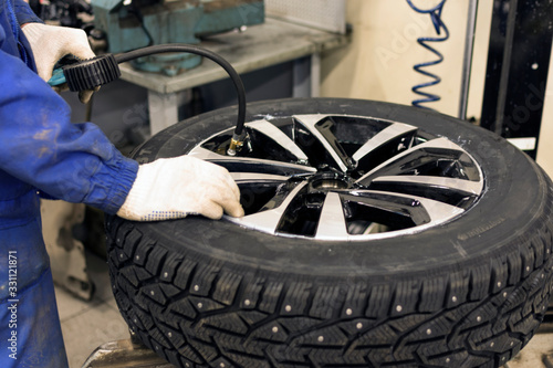 Seasonal winter tire service. Professional mechanic in a car service. A car wheel on a machine for replacing tires. A mechanic at work.