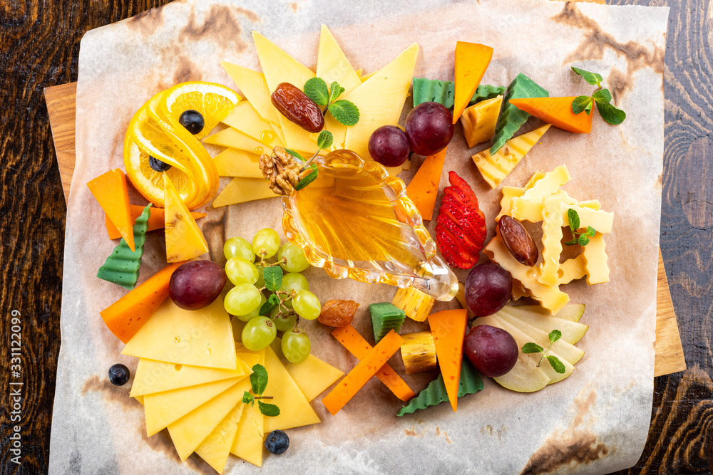 cheese slices with grapes and fruits on paper and wooden background cheese slices with grapes and fruits on paper and wooden background