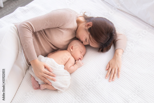Asian beautiful mom motherhood lie down nursing hug newborn baby infant toddler, gently kiss, hold together on chest with love, infant sleep comfortable with safe and protection by mother taking care