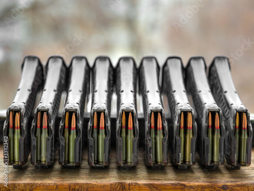 A lot of loaded .223 rifle magazines stacked on a table. photo