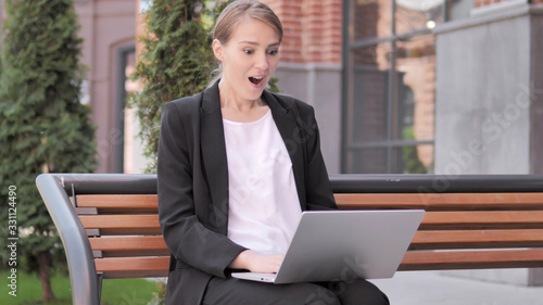 Excited Young Businesswoman Using Laptop Sitting Outside Office