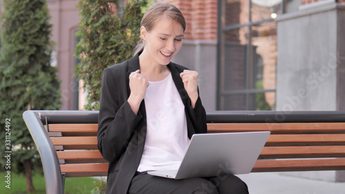 Young Businesswoman Celebrating on Laptop Sitting Outside Office