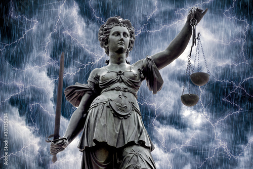 Foto Die Justitia, das Wahrzeichen der Gerichtsbarkeit vor dramatischem Himmel