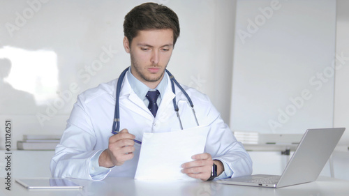 Young Doctor Reading Medical Report, Doing Paperwork