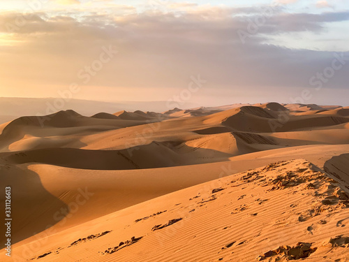 Wahiba Sand desert landscape of Sultanate of Oman - Curvy sand dunes pattern at sunset with cloudy sky. photo