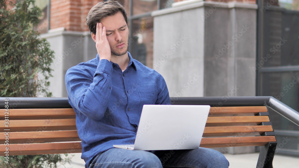 Sitting Outdoor Young Man with Headache Using Laptop Sitting Outdoor Young Man with Headache Using Laptop