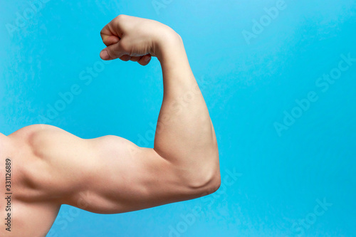 Fotografia Male arm with large muscles close-up, rear view, blue background