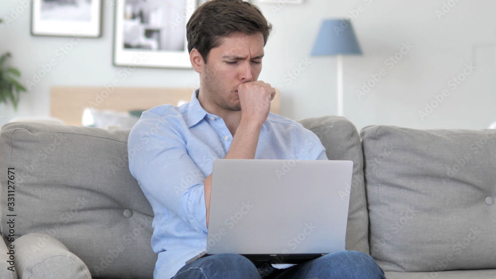 Sick Handsome Young Man Coughing while Working on Laptop at Creative Office Sick Handsome Young Man Coughing while Working on Laptop at Creative Office