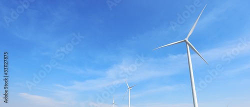 Wind turbine against cloudy blue sky background © nimon_t