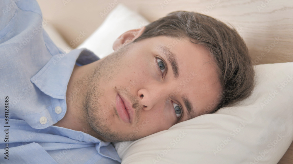 Close Up of Thinking Young Man Lying on Side in Bed Close Up of Thinking Young Man Lying on Side in Bed